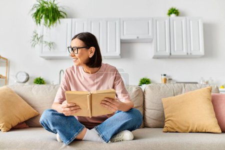 Woman in cozy homewear engrossed in a book while seated on a plush couch.