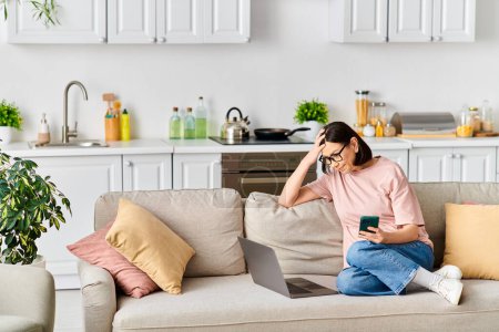 Eine Frau in bequemer Homewear sitzt auf einer Couch, in ihr Handy vertieft.