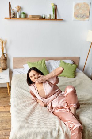 A mature woman in pink pajamas lays peacefully on a cozy bed.