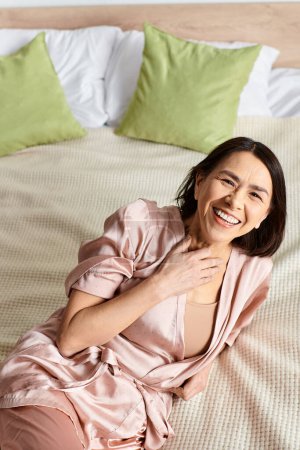 A woman in cozy homewear lounging on a bed surrounded by pillows.