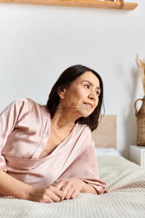 Mature woman in cozy homewear lying on top of bed.