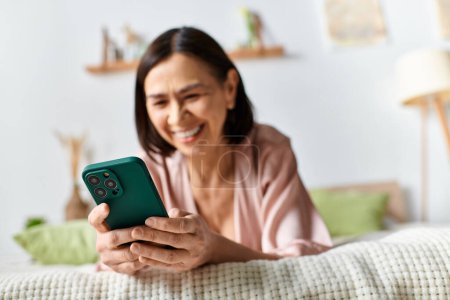 Téléchargez les photos : Une femme en tenue confortable se détend sur un lit, absorbée dans son téléphone portable. - en image libre de droit