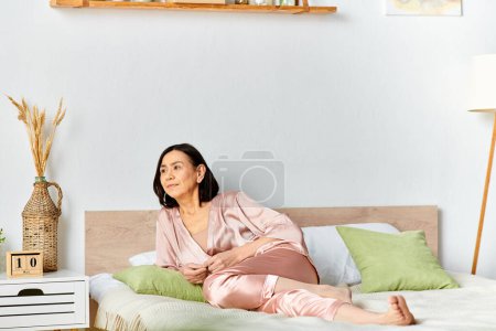 A mature woman in cozy homewear relaxing on top of a bed in a serene room.