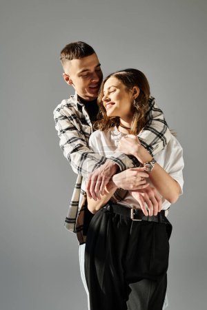 Foto de Un hombre tiernamente sostiene a una mujer en sus brazos, mostrando amor y afecto en un estudio sobre un fondo gris. - Imagen libre de derechos
