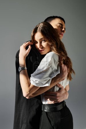 Foto de Un hombre y una mujer en un abrazo amoroso, expresando cercanía y afecto en un estudio sobre un fondo gris. - Imagen libre de derechos