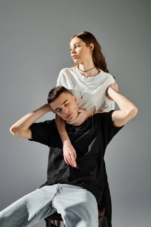 Ein Mann balanciert auf den Schultern einer Frau in einem Studio vor grauem Hintergrund.