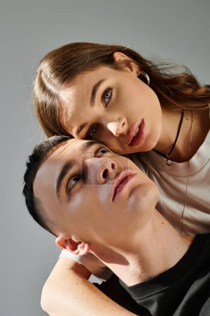 Foto de Un joven hombre y una mujer posan juntos en un estudio sobre un fondo gris, creando una escena amorosa y romántica. - Imagen libre de derechos