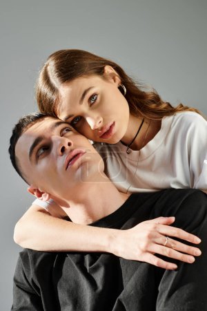 Foto de Un hombre y una mujer jóvenes, profundamente enamorados, posan juntos elegantemente para una foto en un estudio con un fondo gris. - Imagen libre de derechos