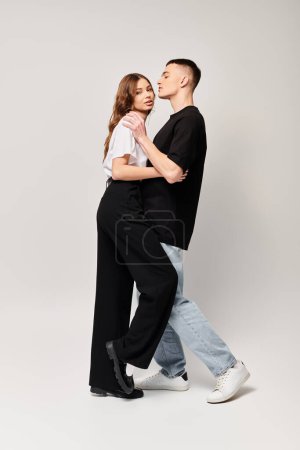 A young couple in love dances together with passion in a studio, against a grey background.