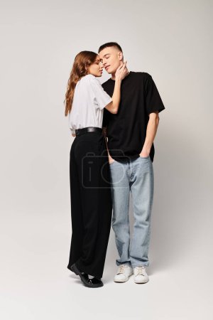 Photo for A young couple in love standing side by side in a studio against a grey background. - Royalty Free Image