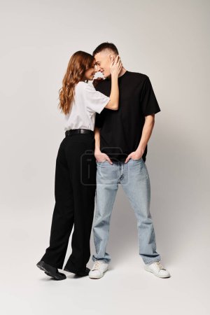 Téléchargez les photos : Un jeune couple, profondément amoureux, se tient côte à côte dans un studio sur fond gris. - en image libre de droit