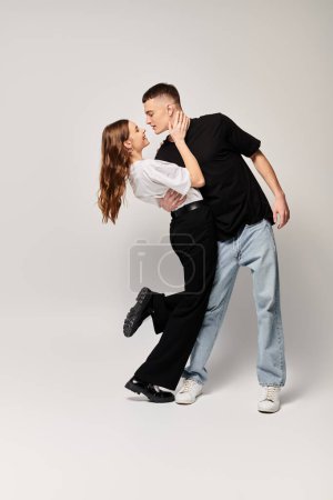 Ein junges verliebtes Paar tanzt anmutig in einem Studio zusammen und zeigt perfekte Synchronisation und gegenseitige Bewunderung.