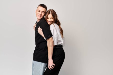 Téléchargez les photos : Un jeune couple amoureux debout côte à côte dans un studio avec un fond gris. - en image libre de droit