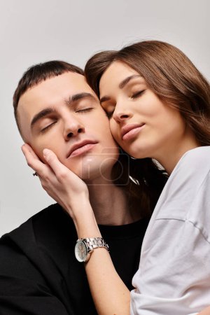 Téléchargez les photos : Un jeune couple, homme et femme, embrassant avec amour dans un studio avec un fond gris. - en image libre de droit