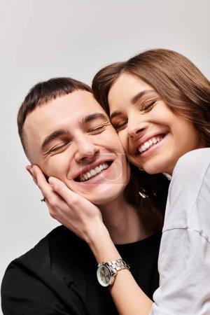 Foto de Un hombre y una mujer compartiendo un abrazo sincero, mostrando amor y afecto en un ambiente de estudio con un fondo gris. - Imagen libre de derechos