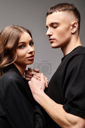 Photo for A young man and woman, standing closely beside each other, exuding love and connection in a studio with a grey background. - Royalty Free Image