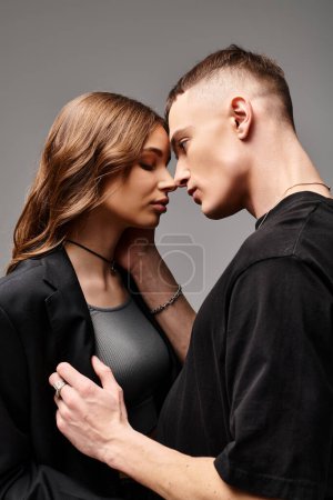 Foto de Un joven hombre y una mujer de pie juntos, mostrando amor y conexión, contra un fondo gris del estudio. - Imagen libre de derechos