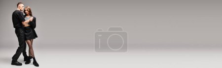 Téléchargez les photos : Un jeune couple se tient uni devant un fond gris neutre. - en image libre de droit