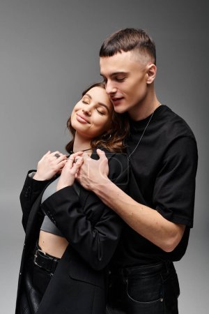 A man and a woman embrace each other in a tender moment of love and connection, against a soft grey background.