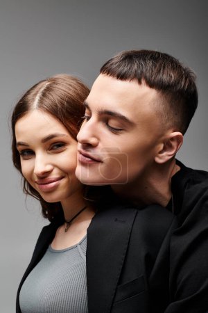 Foto de Un hombre y una mujer, profundamente enamorados, posan para la cámara sobre un fondo gris de estudio. - Imagen libre de derechos