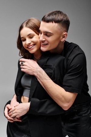 Foto de Un hombre y una mujer se abrazan apasionadamente con un telón de fondo de un estudio gris. - Imagen libre de derechos
