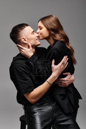 Foto de Una joven pareja enamorada besándose apasionadamente en un estudio con un fondo gris. - Imagen libre de derechos