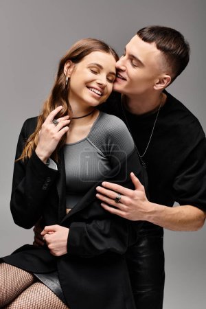 Téléchargez les photos : Un jeune couple amoureux pose dans un studio au fond gris, exsudant grâce et harmonie. - en image libre de droit