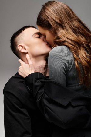 A man and woman share a romantic kiss in a studio, expressing their love for each other against a grey background.