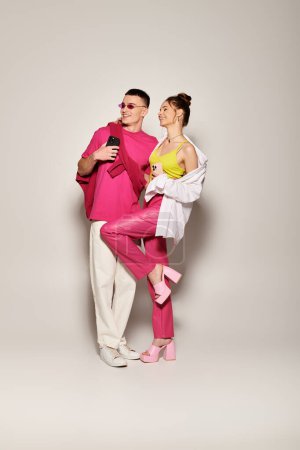 Foto de Una elegante pareja joven enamorada, vestida de rosa y blanco, posa juntos en un estudio sobre un fondo gris. - Imagen libre de derechos
