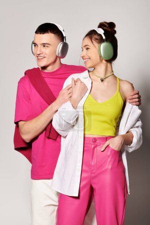 A man and woman, wearing headphones, immerse themselves in music together in a studio with a grey background.