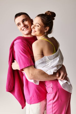 Foto de Una pareja joven y elegante enamorada, abrazándose en un ambiente de estudio con un fondo gris. - Imagen libre de derechos