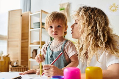 Photo for A curly mother and her toddler daughter engage in the Montessori method of education at a table. - Royalty Free Image