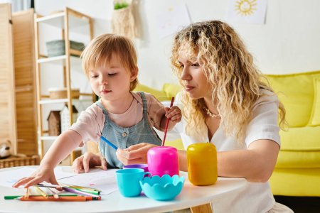 Eine lockige Mutter und ihre kleine Tochter sitzen an einem Tisch und üben sich zu Hause in Montessori-Pädagogik.