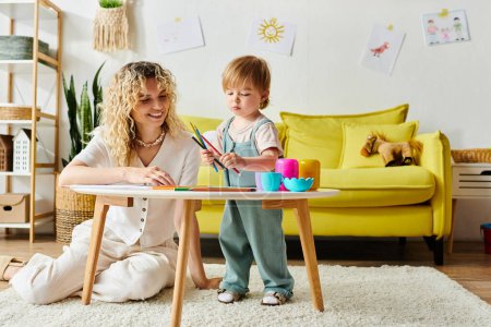 Eine lockige Mutter und ihre kleine Tochter sitzen an einem Tisch und unternehmen zu Hause gemeinsam Montessori-Lernaktivitäten.