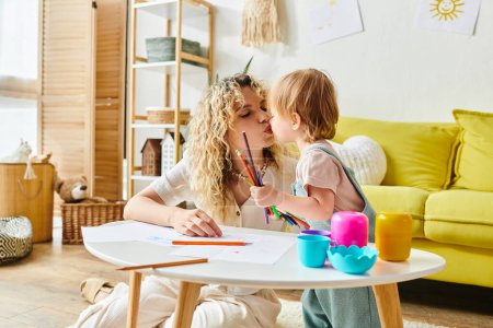 Eine Mutter mit lockigem Haar und ihre kleine Tochter sitzen an einem Tisch und engagieren sich für Montessori-Aktivitäten zur Förderung frühkindlicher Bildung.