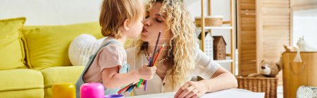Foto de Una madre de pelo rizado besa amorosamente a su hija pequeña en la mejilla en un hogar acogedor utilizando el método Montessori de educación. - Imagen libre de derechos