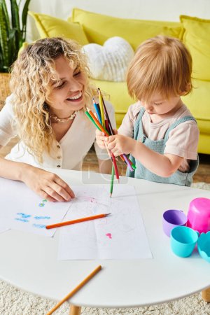 A curly mother and her toddler daughter bonding over crayons using the Montessori method of education at home.