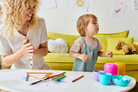 Foto de Una madre rizada y su hija pequeña participan alegremente en la creatividad colorida con lápices de colores utilizando el método Montessori en casa. - Imagen libre de derechos