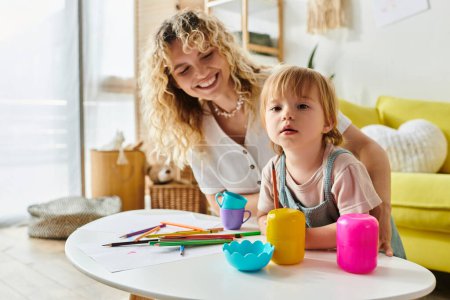 Una madre de pelo rizado y su hija pequeña participan alegremente en el juego basado en Montessori en casa con juguetes coloridos.