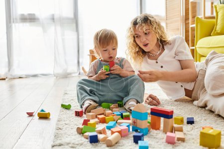 A curly-haired mother and her toddler daughter engage in Montessori play, building together with colorful blocks on the floor.