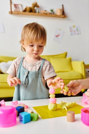 Mutter sieht zu, wie ihre kleine Tochter Montessori-Spielen an einem Tisch voller Spielsachen nachgeht.