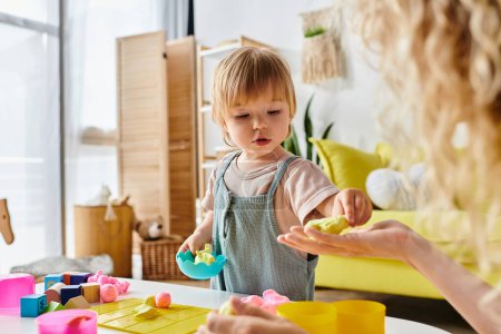 Téléchargez les photos : Mère bouclée tenant tendrement la petite fille, pratiquant l'éducation Montessori à la maison. - en image libre de droit
