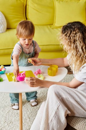 A mother with curly hair and her toddler daughter are immersed in play using Montessori education at home.