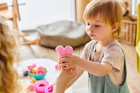 Foto de Una madre rizada empodera a su hija pequeña en el juego Montessori con un juguete colorido y educativo. - Imagen libre de derechos