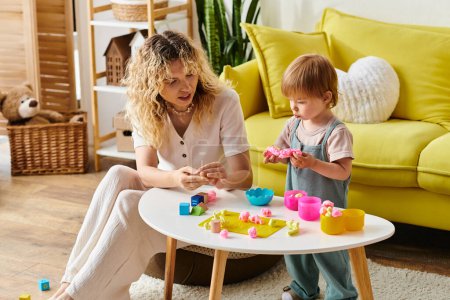 Curly mother and toddler daughter happily playing with toys, practicing Montessori education at home.