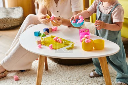 Foto de Madre y su hija pequeña están inmersas en el juego, utilizando juguetes educativos Montessori en casa. - Imagen libre de derechos