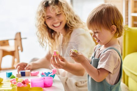 A curly mother and her toddler daughter engage in the Montessori method of education at home, exploring and playing at a table.