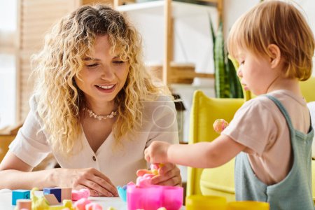 Eine lockige Mutter und ihre kleine Tochter spielen zu Hause fröhlich mit Montessori-Spielzeug.