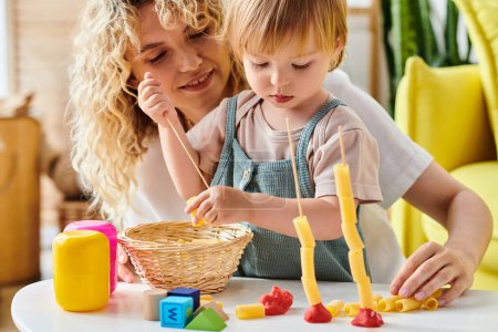 Eine lockige Mutter und ihre kleine Tochter interagieren zu Hause spielerisch mit Montessori-Lernspielzeug.