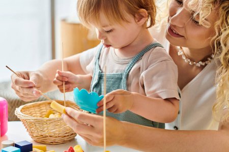 Téléchargez les photos : Une mère bouclée et sa fille enfant jouent avec plaisir avec des jouets éducatifs en utilisant la méthode Montessori à la maison. - en image libre de droit
